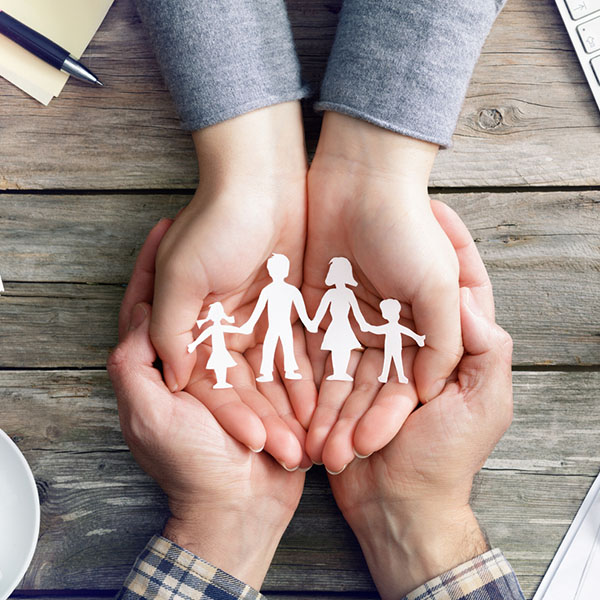 two sets of white hands holding a paper family and discussing term insurance